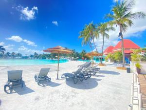 a group of chairs and umbrellas on a beach at TROPIC Appartements PREMIUM village vacances vue mer Guadeloupe St Anne avec piscine in Sainte-Anne