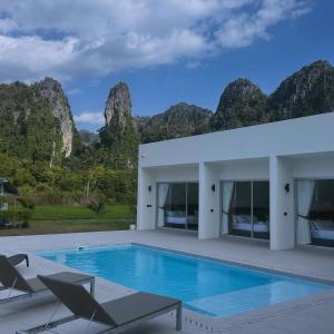 een zwembad met stoelen en bergen op de achtergrond bij วันทน่า พูลวิลล่า เนินมะปราง in Ban Mung