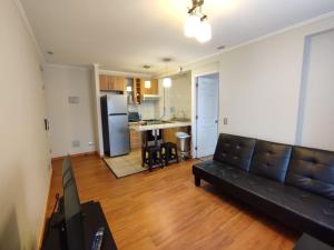 a living room with a couch and a kitchen at Privado y Acogedor in Puerto Montt