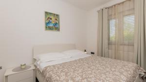 een witte slaapkamer met een bed en een raam bij Villa FourM - Makarska by Villas Guide in Novak +31 foto's