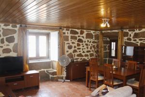 a living room with a television and a table and chairs at Casa Castro - Refúgio Rural em Fonte Arcada, Silêncio e Conforto in Fonte Arcada
