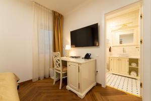 ein Hotelzimmer mit einem Schreibtisch und einem Fernseher an der Wand in der Unterkunft Casa Doseanu in Oradea