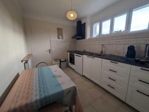 een keuken met witte kasten en een tafel. bij Villa jeandor in Braucourt +12 foto's