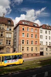 un bus jaune circulant dans une rue à côté des bâtiments dans l'établissement Hostel Alex 30, à Stuttgart