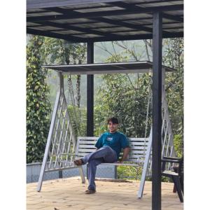 een jongen die op een schommel op een veranda zit bij Sylora Meadows Private Pool Villa ,Vagamon in Pīrmed