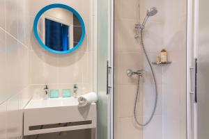 een badkamer met een douche, een spiegel en een wastafel bij Hostel Ozz Nice in Nice