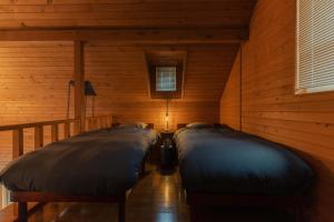 twee bedden in een kamer met houten wanden bij Mokurie in Teshikaga
