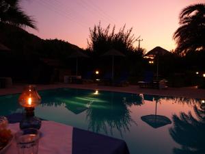una candela seduta su un tavolo accanto alla piscina di Villa Rhapsody Pension a Kayakoy