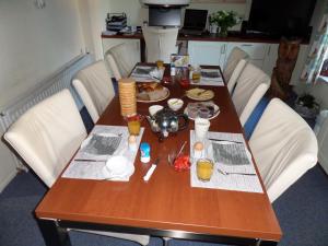 una mesa de madera con sillas blancas alrededor en B&B Huize Cossee, en Gasselte