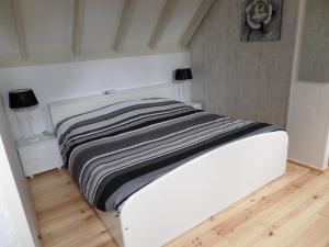Cama blanca en habitación con suelo de madera en B&B Huize Cossee, en Gasselte