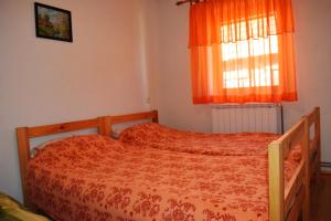 a bedroom with a bed with an orange comforter and a window at Apartment Doris Mrkopalj in Mrkopalj