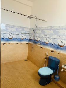 een badkamer met een blauw toilet en een schilderij van vogels bij Lyra Mirissa in Mirissa