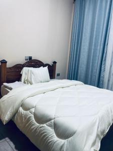een slaapkamer met een groot wit bed en blauwe gordijnen bij Kingston apartment in Kigali