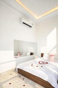 Ein weißes Schlafzimmer mit einem großen Bett und Rosen auf dem Boden in der Unterkunft Bảo Ngọc Hotel Đông Hà in Quang Tri