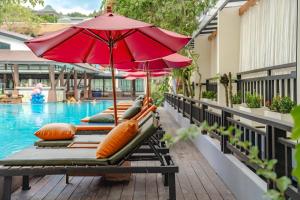 een rij ligstoelen met parasols naast een zwembad bij Phuvaree Resort in Patong Beach