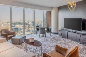 Hilton Riyadh Olaya في الرياض: غرفة معيشة مع تلفزيون وطاولة وكراسي