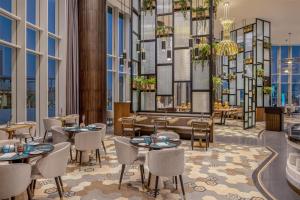Hilton Riyadh Olaya في الرياض: مطعم به طاولات وكراسي ونوافذ