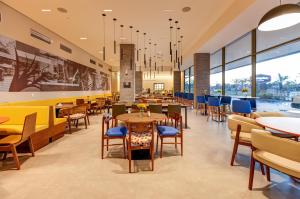 ein Restaurant mit Tischen, Stühlen und Fenstern in der Unterkunft Hampton By Hilton Caraguatatuba Serramar in Caraguatatuba