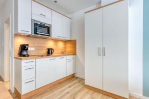 eine Küche mit weißen Schränken und einer Mikrowelle in der Unterkunft Alte Teestube Schmidt 68 in Norderney