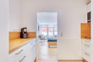 a kitchen with white cabinets and a door leading to a bedroom at Alte Teestube Schmidt 58 in Norderney
