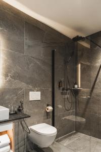 a bathroom with a toilet and a glass shower at Falcon Suites Pure - Summercard included in Kaprun +43 photos