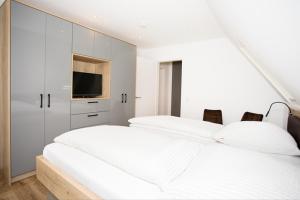 - 2 lits dans une chambre blanche dotée d'une télévision dans l'établissement Klosterhof Aue W 7, à Bad Zwischenahn