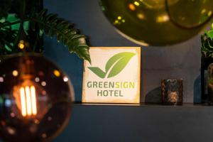 a green system hotel sign on a shelf with a vase at Cocoon Sendlinger Tor in Munich +107 photos