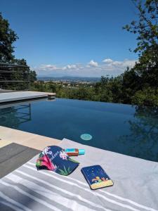 Ein Tisch mit zwei Büchern darauf neben einem Schwimmbecken in der Unterkunft La romarine in Bourg-Saint-Andéol