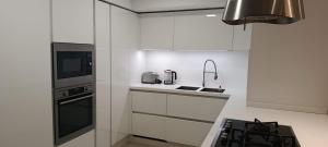 een witte keuken met een spoelbak en een fornuis bij Interlace penthouse with swimming pool in Il-Ħamrija