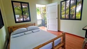 a bedroom with a bed and two windows at Suki Beach Resort Beachfront Cottage in Santa Magdalena