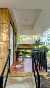 a porch of a house with a bench and a table at Suki Beach Resort Beachfront Cottage in Santa Magdalena