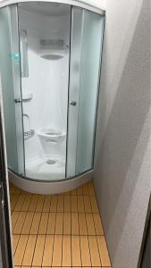 een glazen douche in een kamer met een houten vloer bij 宿屋しの軒 1階 in Kirishima
