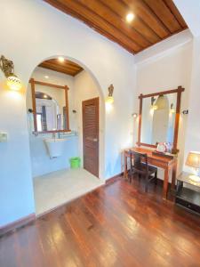 een badkamer met een wastafel, een bureau en een spiegel bij Villa Xiengthong Garden View in Luang Prabang
