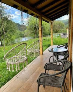 a porch with four chairs and a table on a deck at Cozy Rest House in Verkhovyna