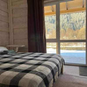 a bedroom with a bed and a large window at Cozy Rest House in Verkhovyna