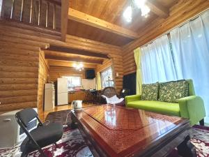 a living room with a green couch and a table at コテージ杏庵 Cottage Anzuan in Minamioguni