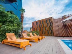 una fila de bancos de madera sentados junto a una piscina en Loft Mania Boutique Hotel en Chumphon