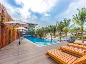 a pool with chairs and an umbrella on a deck at Loft Mania Boutique Hotel in Chumphon