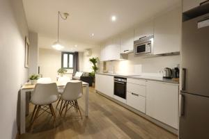une cuisine avec des armoires blanches et une table et des chaises dans l'établissement Bravissimo Força 17, Barri Vell apartments, à Gérone