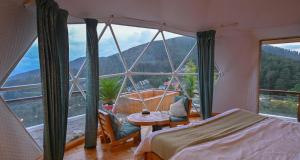 卡绍利Glamp Retreat Kasauli的一间卧室，里面有一张床和一扇大窗户。