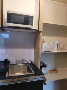 een keuken met een spoelbak en een magnetron bij Villa in Bellevue in Tauranga