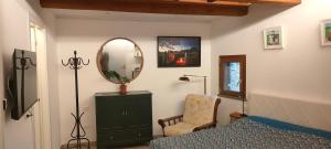 een slaapkamer met een bed, een spiegel en een stoel bij Locanda delle fonti in Bassano in Teverina