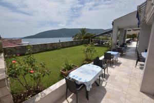 a patio with tables and chairs and a view of the water at Hotel Vila Margot in Herceg-Novi