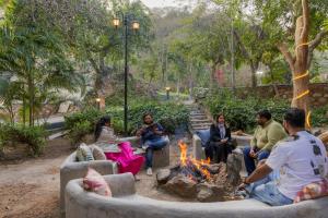 a group of people sitting around a fire pit at SaffronStays Grand Pavilion in Udaipur +49 photos
