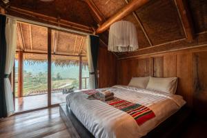 a large bed in a room with a large window at Pù Luông Ecolodge in Pu Luong