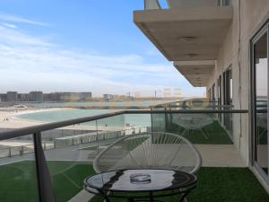 a balcony with a table and a view of the beach at ZAPBED HOUSE -1 BR In Pacific Tower Al Marjan Island With Beach Access Ras Al Khaimah in Ras al Khaimah