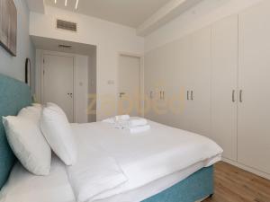 a white bed with white pillows in a bedroom at ZAPBED HOUSE -1 BR In Pacific Tower Al Marjan Island With Beach Access Ras Al Khaimah in Ras al Khaimah