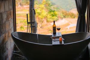 a bath tub with a bottle of wine and a glass at Pù Luông Ecolodge in Pu Luong
