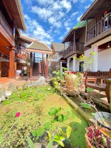 een tuin met een vijver voor een gebouw bij Villa Xiengthong Garden View in Luang Prabang