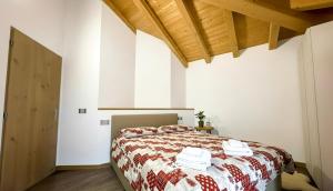 a bedroom with a bed with a red and white blanket at Paradiso di Grosio - mansarda con vista montagne in Grosio